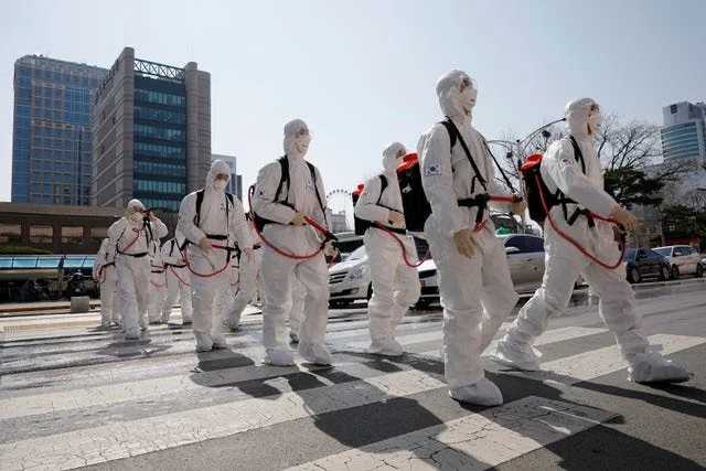 South Korean soldiers wearing protective gear walk on a street in front of Daegu's city hall after the rapid rise in confirmed cases of the coronavirus on March 2, 2020. Photo by Reuters.